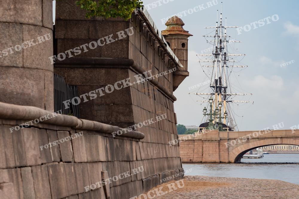 На фотографии изображена Нева и часть Петропавловской крепости в Санкт-Петербурге с фокусом на мачты корабля. 
Это изображение подойдёт для исторических работ, туристических публикаций, образовательных материалов о Санкт-Петербурге или как фотография для офисного или жилого декора, отражающая морскую тематику.